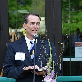 John McVay talks in a microphone in front of the ad building